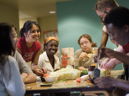 Several smiling UMBC students gathering around a table