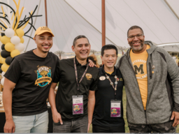 Four UMBC alums at a reception in a tent