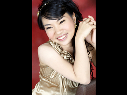 Pianist Hui-Chuan Chen smiles at the camera as she clasps her hands.