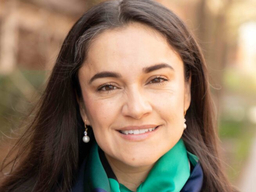 A Mexican-American-Indian woman is smiling. She has long dark camera