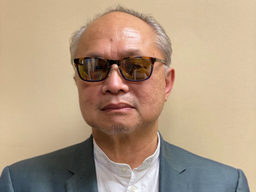 An older man is wearing sunglasses and a suit.