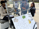 Dr. Yvette Mozie Ross, Vice Provost of Enrollment Management sitting on a golf cart with a sign that reads "Cash Cart" surrounded by curious students.