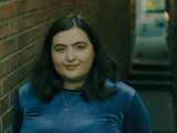 A head and shoulders shot of Johanna standing by a brick wall with steps behind her.