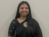 Noreen smiling and standing with a gray background